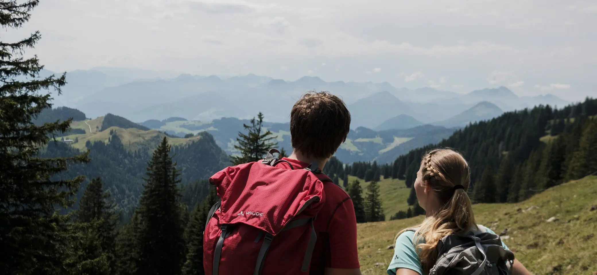 Ein Mann und eine Frau beim Wandern Wanderer in den Chiemgauer Alpen - sie genießen den Ausblick über mehrere Gipfel. | © DAV/Hans Herbig